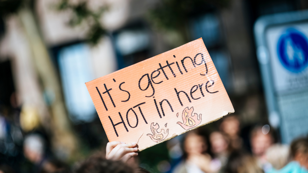 A hand holding a cardboard, saying it's getting hot in here, implying that the Earth is getting hotter and we should switch to R290 refrigerant